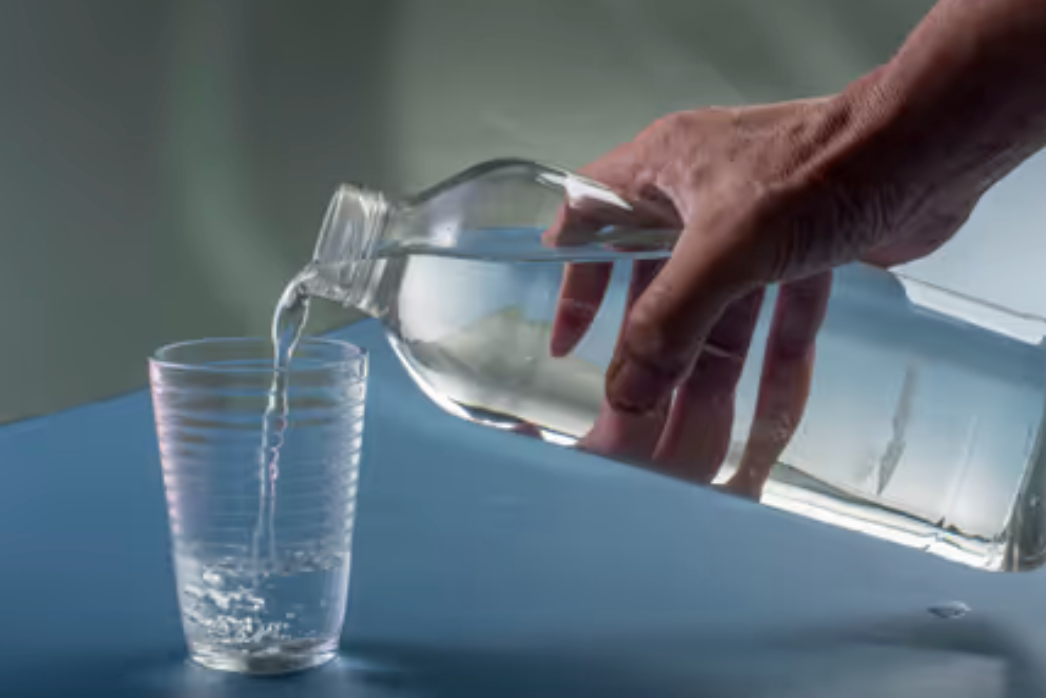 Persona sirviendo agua en un vaso, concepto de hidratación